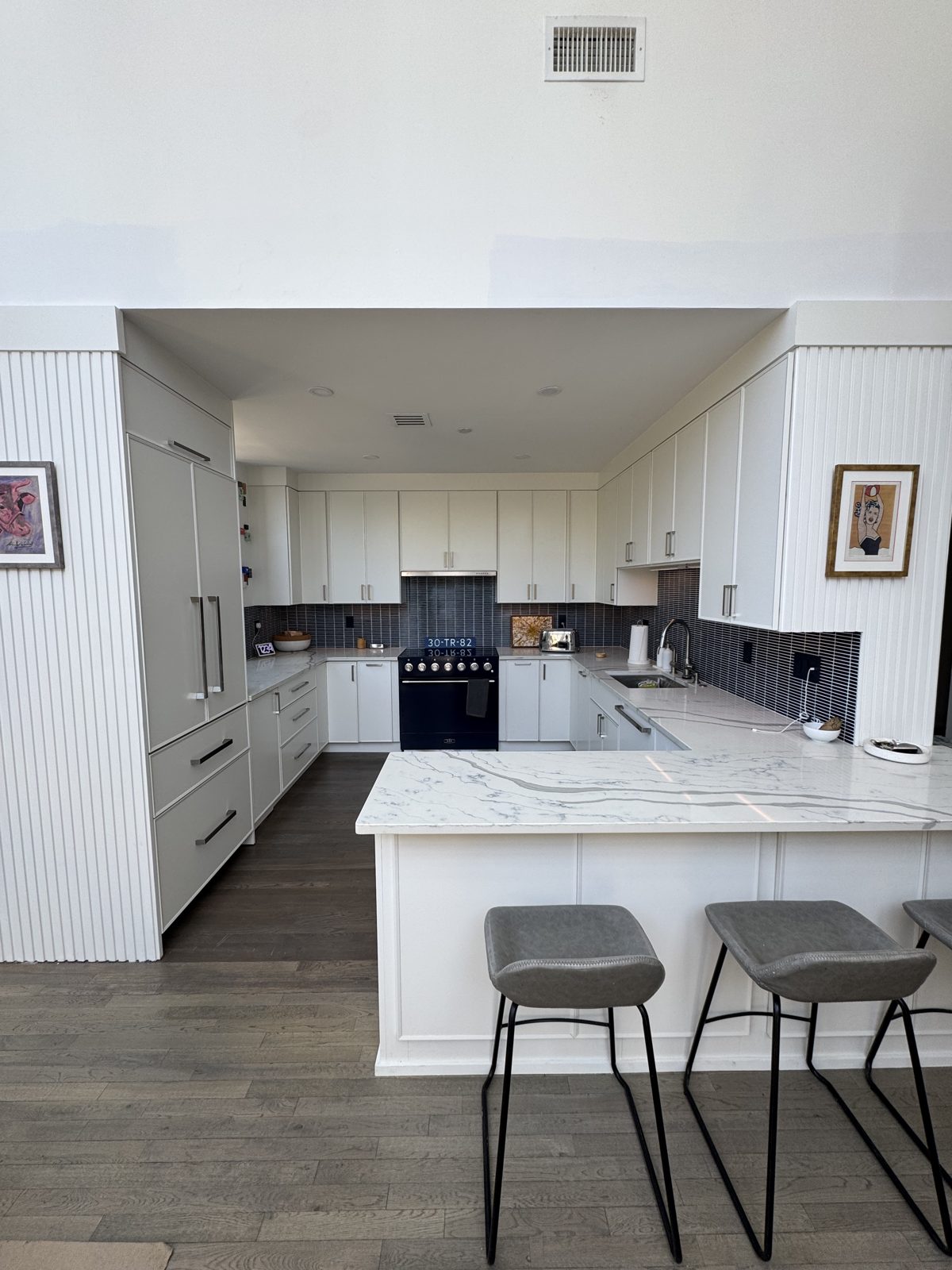 Kitchen after full renovation — white cabinets, waterfall quartz peninsula with seating, Glen Ridge NJ