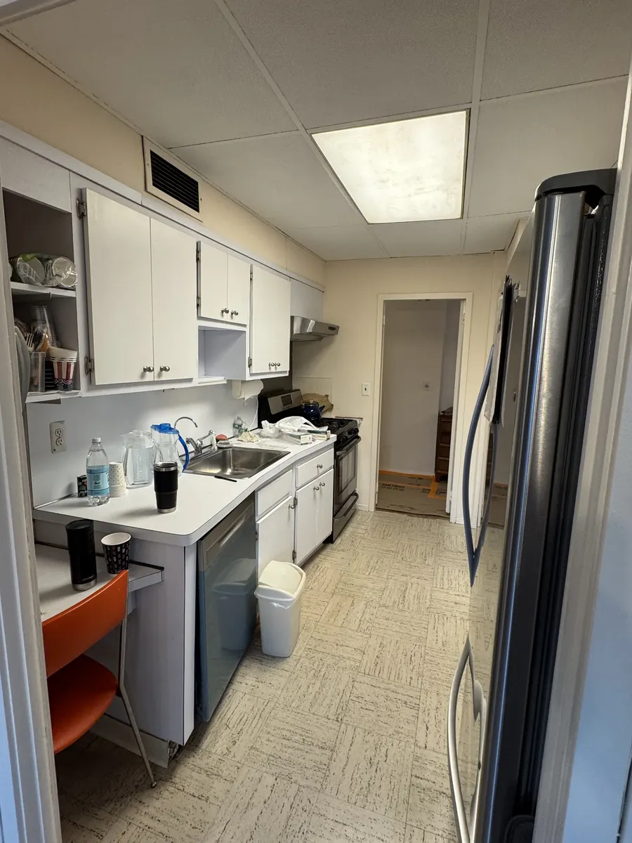 Before: narrow Glen Ridge galley kitchen with older white cabinets, dropped ceiling, and a doorway at the end