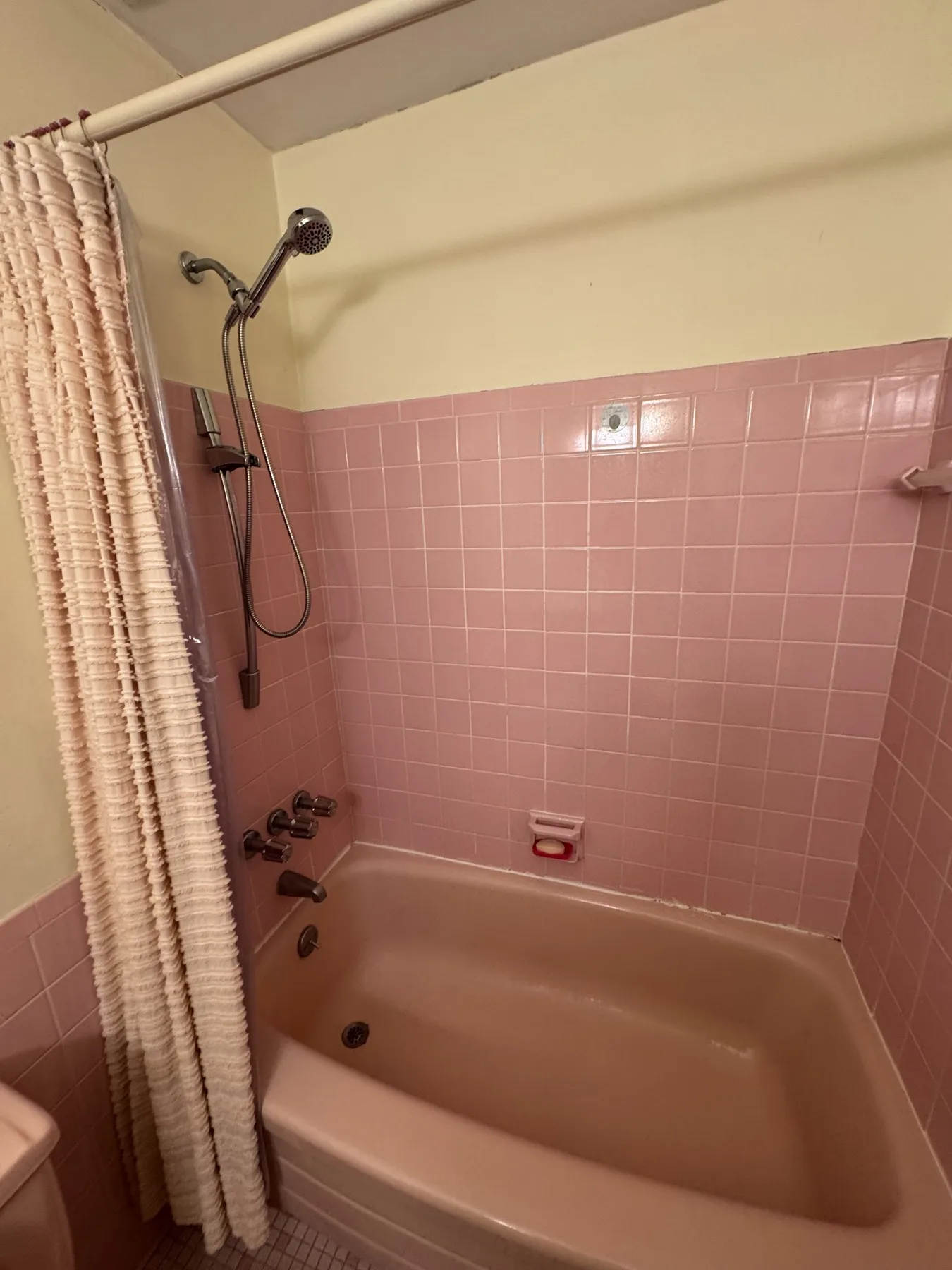 Before renovation: original pink bathtub and pink tiled surround in the Glen Ridge apartment bathroom