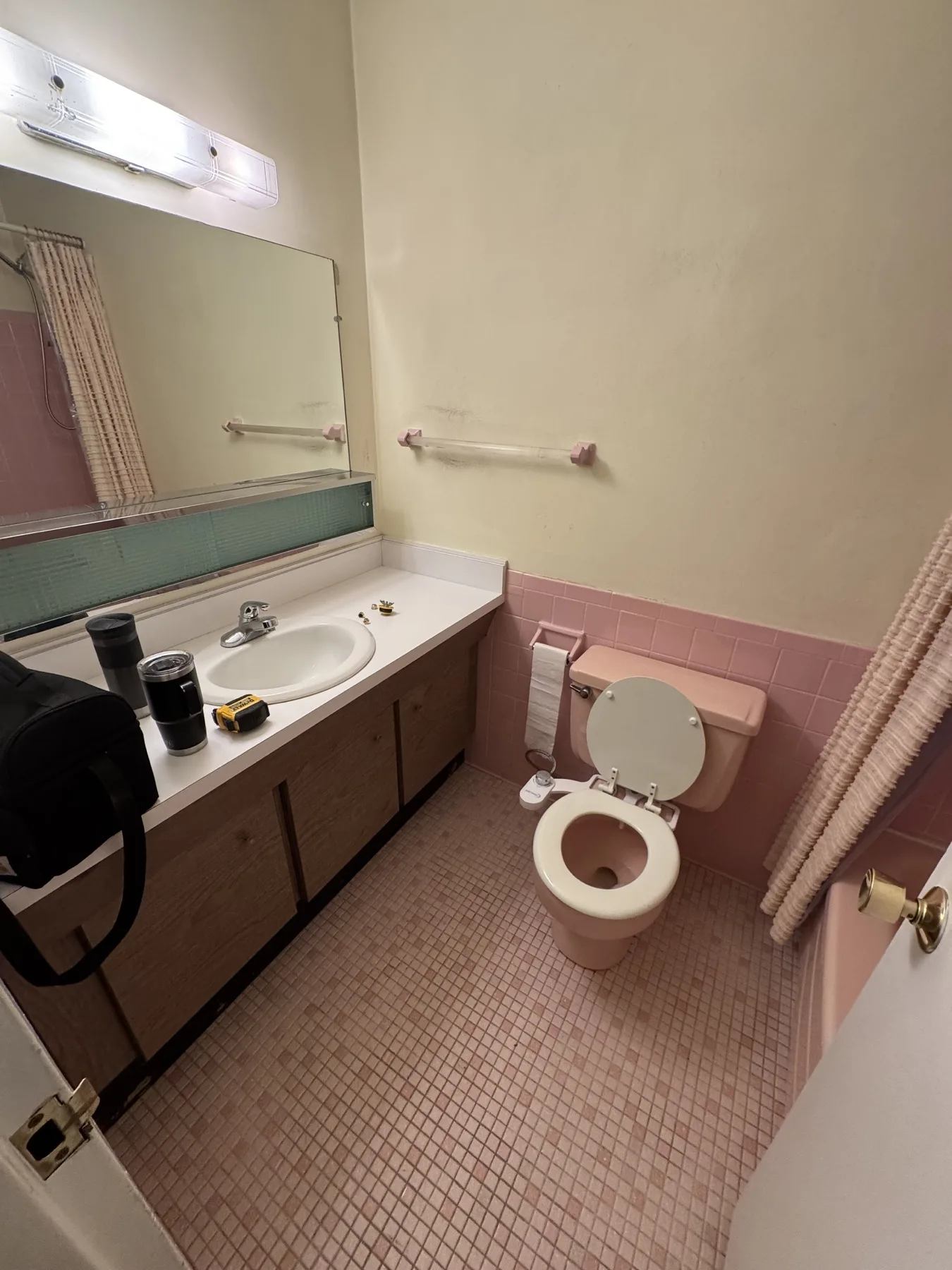 Before renovation: original wood vanity, toilet, and pink tile in the Glen Ridge apartment bathroom