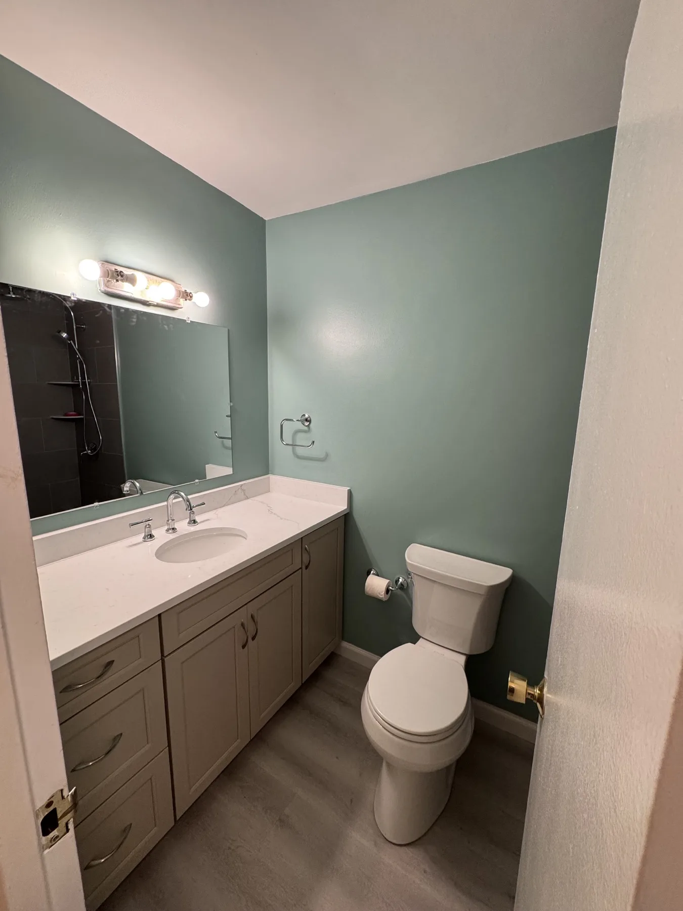 Finished Glen Ridge apartment bathroom with blue-green walls, gray vanity, light countertop, and new toilet